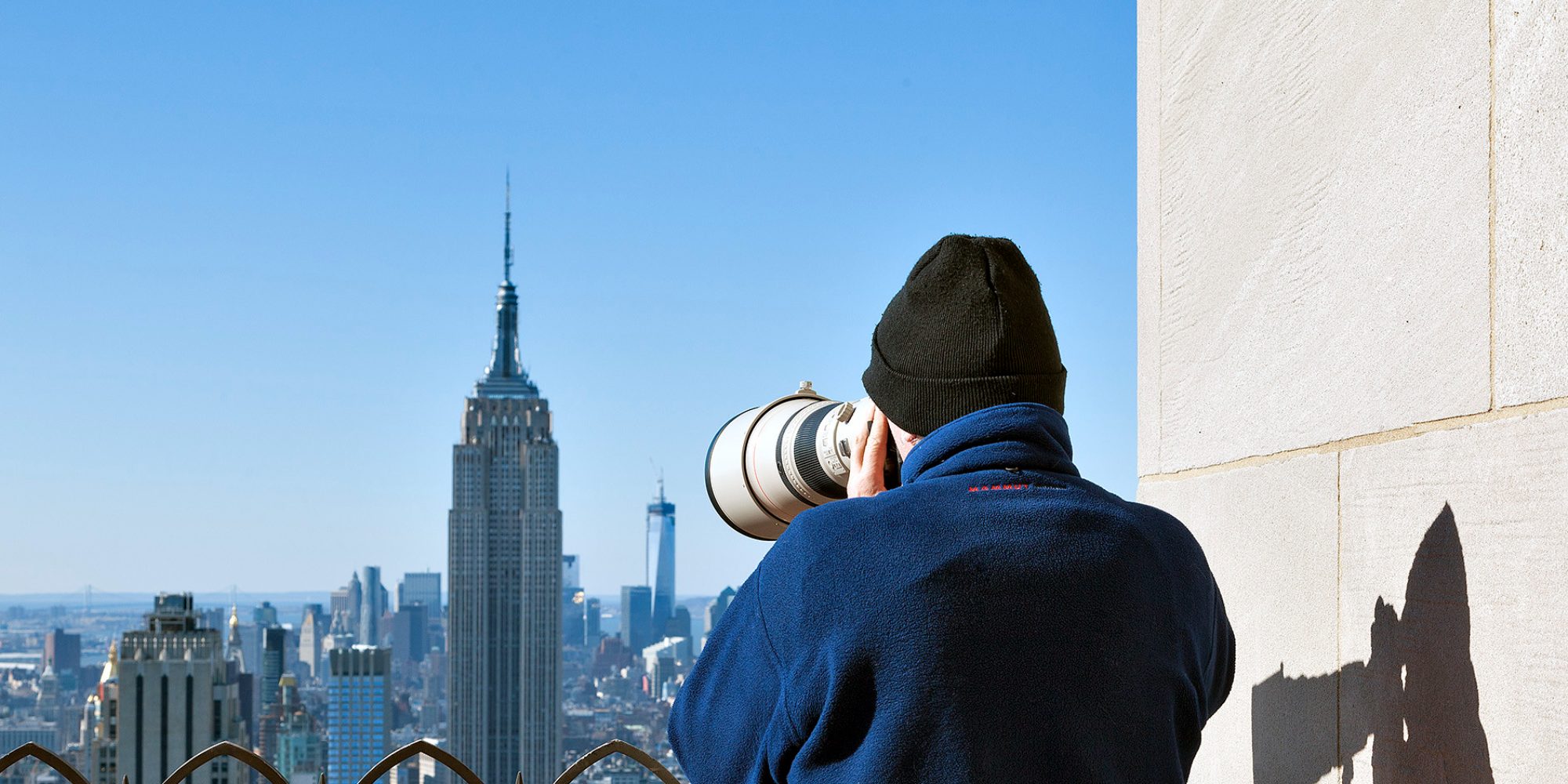 A man taking a picture of the Rockefeller Center.
