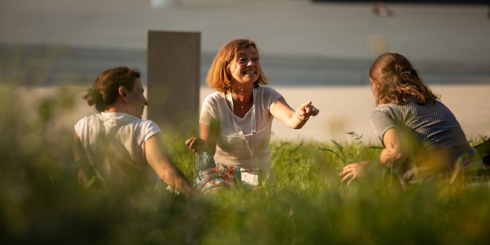 Photo showing a group of people sitting in the grass.